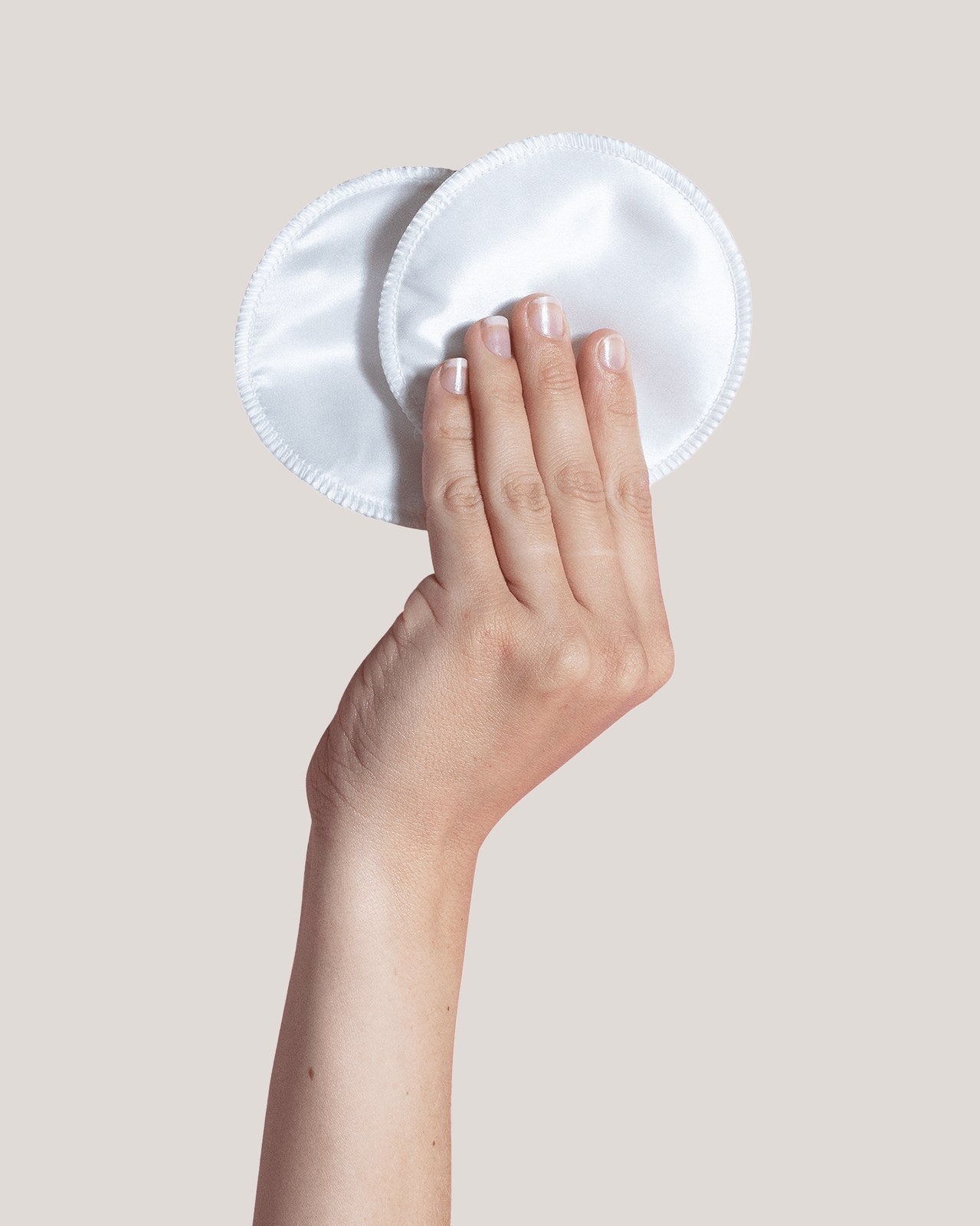 Hånd holder to hvide Carriwell ammeindlæg i blød silke